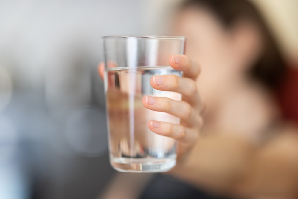 Person holding a clear glass of water