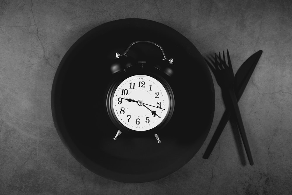 Alarm clock on a plate with cutlery representing a fasting eating window schedule